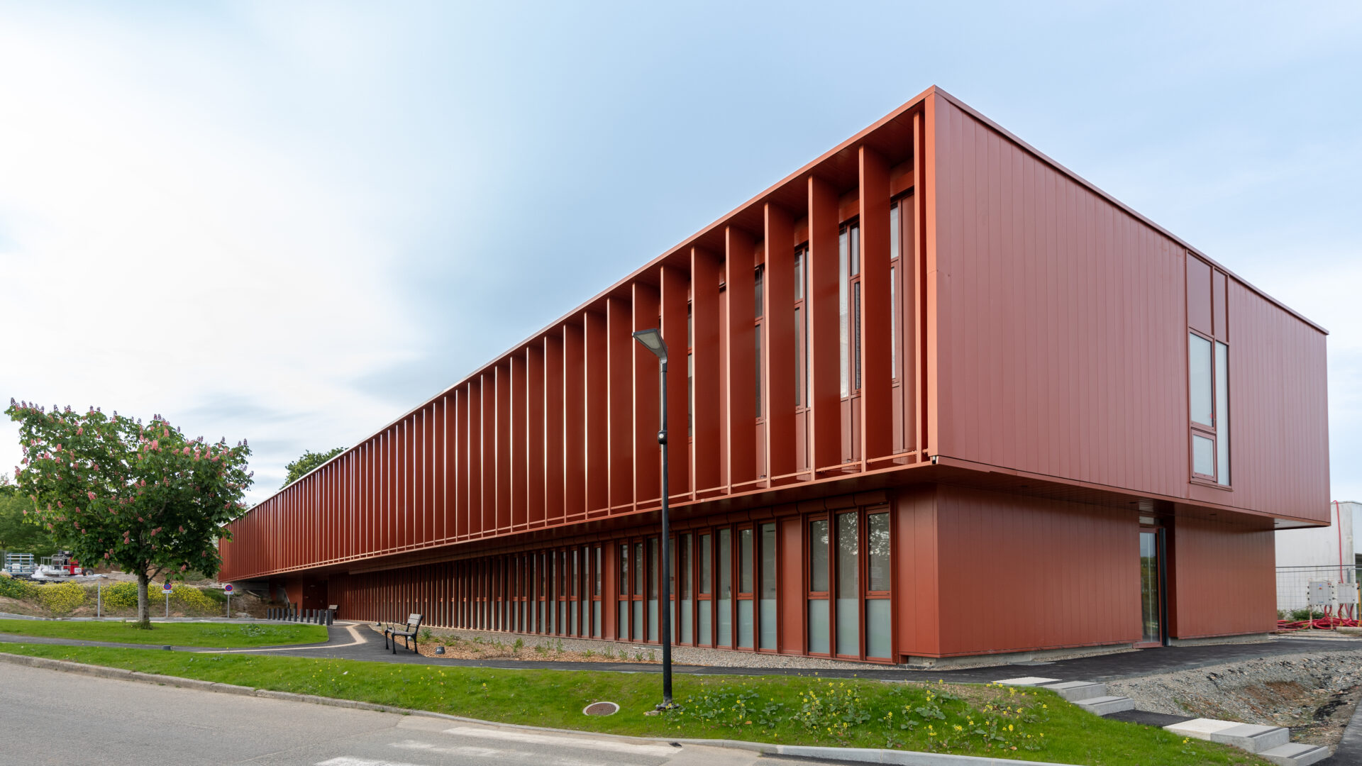 Vue extérieure du Centre Hospitalier de Douarnenez, un projet d'architecture médicale d'A26, mettant en avant la durabilité et l'efficacité énergétique avec son design moderne et ses espaces verts intégrés.