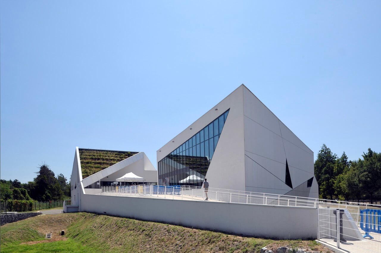 Le centre aquatique A26 avec toiture végétalisée et design géométrique unique, illustrant une approche innovante en termes de développement durable et de réduction de l'empreinte énergétique