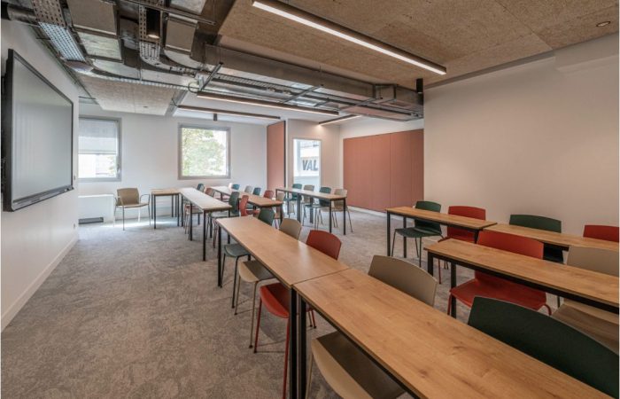 Salle de réunion contemporaine imaginée par A26 Architectures, illustrant la transformation de l'espace de bureau avec un design supportant le changement de destination d'usage, équipée pour le travail collaboratif et individuel.